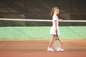 Little girl playing tennis on court
