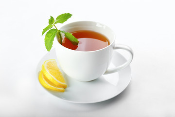 Cup of hot aromatic tea with lemon and mint on white background