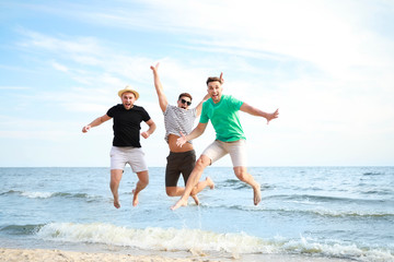 Happy jumping friends on sea beach at resort