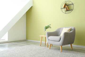 Soft armchair and table with eucalyptus branches in interior of room