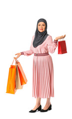 Beautiful mature Muslim woman with shopping bags on white background