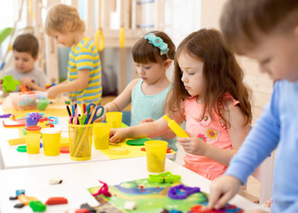 Art and craft activity in kindergarten. Preschool kids hands working in day care center. Group of children engaged in handcrafts - obrazy, fototapety, plakaty