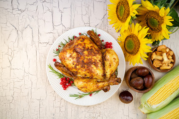 Thanksgiving background. Roasted whole chicken or turkey with autumnal vegetables, mushrooms and berries for thanksgiving dinner on wooden table. Thanksgiving Day concept. Top view, copy space