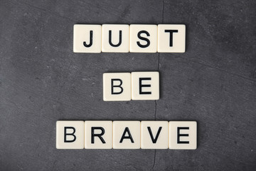 A motivational quote Just be brave formed with tile letters