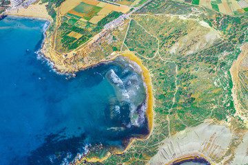 Coast with a beach among the rocks and stones on the ocean, aerial top view.