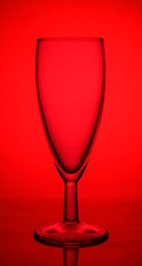 empty glass champagne glass on the lumen on a red background