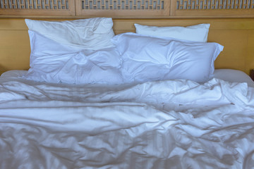 The mattress after use has pillows and blankets that are wrinkled.
