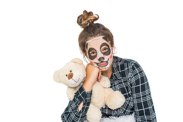 Young teenage girl with facial panda mask looking at camera isolated on white background. Cosmetic...