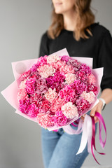 Mono bouquet. Bunch of carnation flowers rich pink color. Spring bunch in woman hand. Present for Mothers Day.