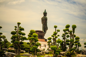 Obraz premium Standing buddha for worship in Phutthamonthon Park with sunset sky and reflective light,beautiful background