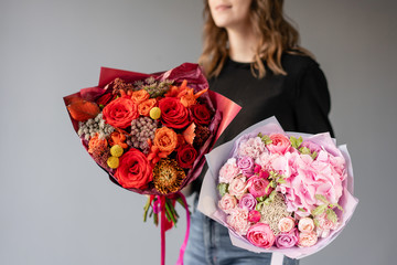 Two Beautiful bouquets of mixed flowers in womans hands. the work of the florist at a flower shop. Fresh cut flower. Red and pink color