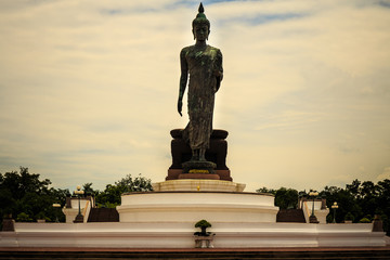 Obraz premium Standing buddha for worship in Phutthamonthon Park with sunset sky and reflective light,beautiful background