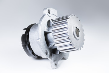 New metal automobile pump for cooling an engine water pump on a gray background with a gradient. The concept of new spare parts for the car engine