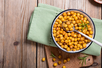 Roasted chickpeas, vegan healthy snack, baked spicy chickpeas on wooden background
