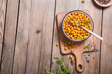Roasted chickpeas, vegan healthy snack, baked spicy chickpeas on wooden background