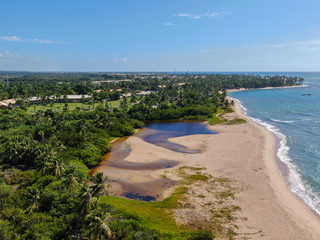 Fototapeta na wymiar Aerial view of river merging to tropical white sand beach and turquoise clear sea water. Praia do Forte, Bahia, Brazil. Travel tropical destination