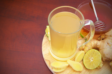 Hot ginger tea with lime and honey on board on red table