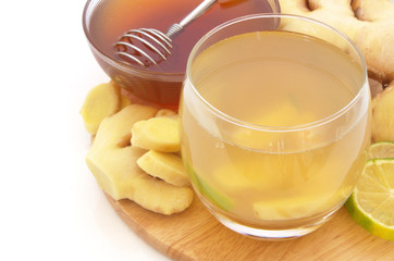 Ginger tea glass, lime and honey on wooden board