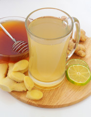 Fresh hot ginger tea with lime and honey on cutting board