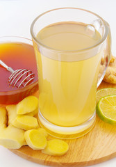 Ginger tea cup, lime and honey on wooden board