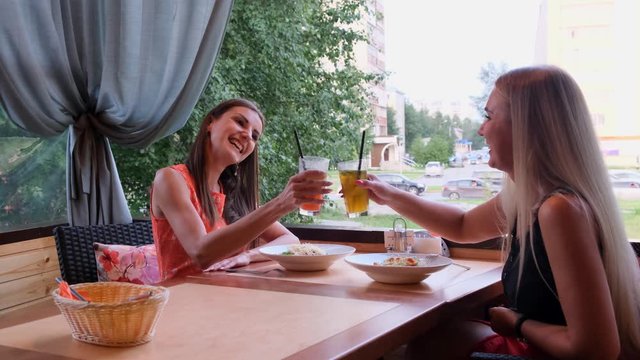 Two friends in a cafe-bar drink cocktails on an open terrace.
