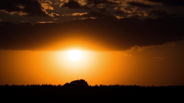 Dramatic Sunset through the Clouds above the Horizon. Timelapse.