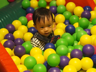 Fototapeta na wymiar Baby boy playing plastic balls in ball pool