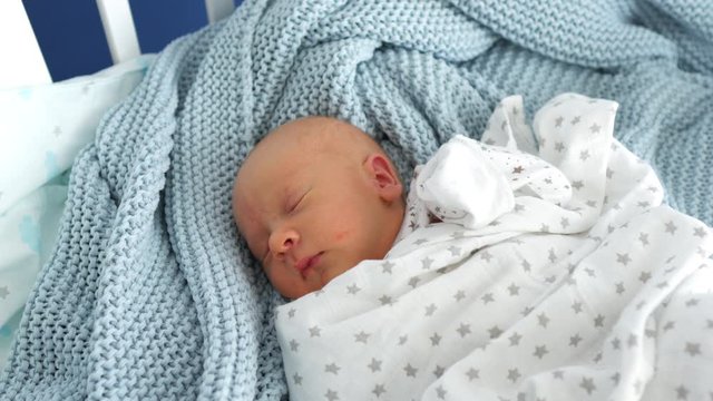 newborn baby sleeps on a blue plaid