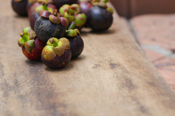 Fresh red and purple mangosteen on wood table. Queen of fruit, good for Anti-anging. Asian local Thai fruit with white fruit after peeling hard shell.