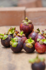 Fresh red and purple mangosteen on wood table. Queen of fruit, good for Anti-anging. Asian local Thai fruit with white fruit after peeling hard shell.