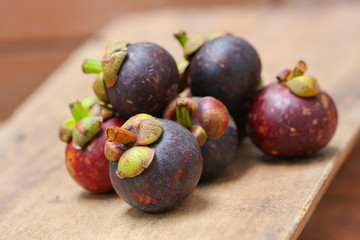 Fresh red and purple mangosteen on wood table. Queen of fruit, good for Anti-anging. Asian local Thai fruit with white fruit after peeling hard shell.