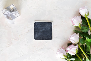 Valentines day greeting card. Pink roses and gift box with small chalk boards on light stone...