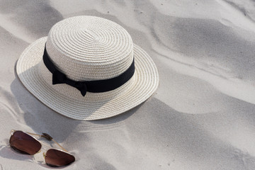 Fototapeta na wymiar Sunglases, summer straw hat on sandy background