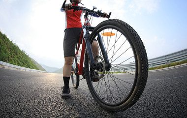 Fototapeta premium Woman cyclist riding mountain bike on highway