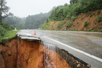 landslide caused by torrential rains occurs broken road asphalt. Broken cement on street. Cracked road from landslid destroyed by heavy rain