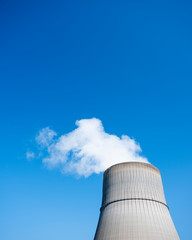 steam and blue sky above large chimney of nuclear power plant near lingen in lower saxony