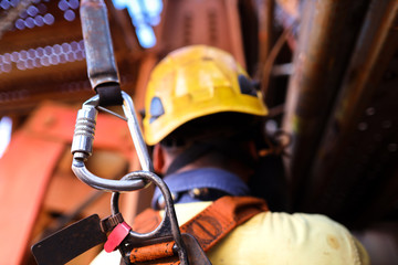Construction worker welder wearing safety helmet, fall arrest harness clipping locking Karabiner...