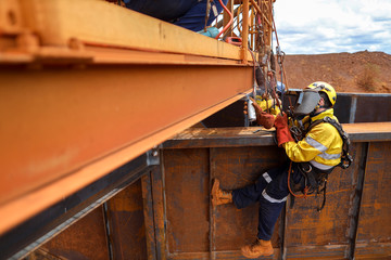 Rope access painter maintenance abseiler wearing fall safety body harness helmet protective gear applying cane rust proof paint spraying first coating paint construction mine site, Perth, Australia  