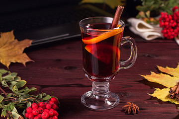 Glass of mulled wine on a wooden table with cinnamon.