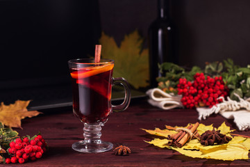 Glass of mulled wine on a wooden table with cinnamon.