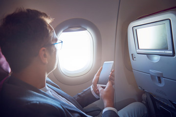 Man using cellphone to take photos through the airplane window.