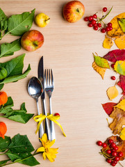 Fall or autumn themed place setting with a knife, spoon and fork, colorful leaves, copy space for text