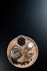 top view a cup of hot coffee espresso in a transparent cup on top foam milk beautiful latte art with coffee beans brown sugar and milk on black table.