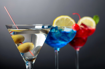 Two colorful cocktails and dry martini with green olives.