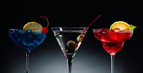 Two colorful cocktails and dry martini with green olives.