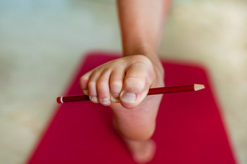 Girl doing exercises with a pencil for toes. Close-up