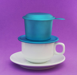 Vietnamese drip coffee, small coffee cup and blue metallic phin on purple background