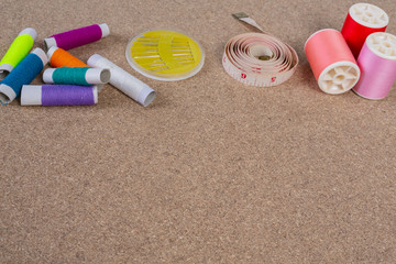 Dressmaking equipment, thread needle placed on a brown plywood floor.