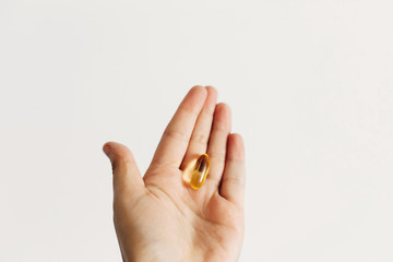Hand holding omega 3 capsule on white wall background. Morning dose of vitamin. Fish oil in pills. Dietary supplements. Health support and treatment. Biologically active additives