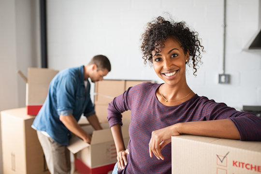 Woman leaning on cardboard box while moving house